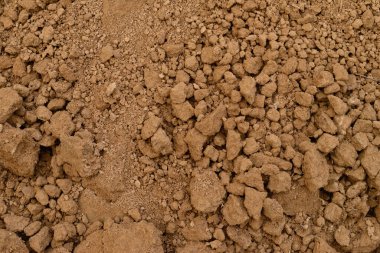 Kuru kil toprağın tam çerçeve arka planı, doğal topaklar ve pürüzlü doku. Ziraatte, bahçıvanlıkta ya da inşaatta kullanılan kahverengi toprak yüzeyine yakından bakın.