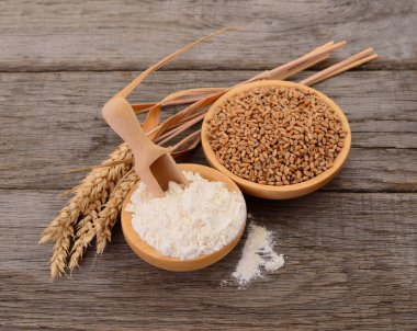 Tahta kaselerde buğday taneleri ve un. Köy ahşap masada kepçe, doğal pişirme ve tarım malzemeleri.