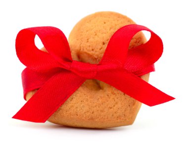 Kalbinde kırmızı saten kurdeleyle süslenmiş tatlı kurabiyeler. Sevgililer Günü için romantik bir tatlı ya da beyazlar içinde izole edilmiş bir düğün. Aşk ve kutlama konsepti.