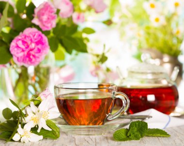 Güneşli bir günde bir fincan çay ve çiçek.