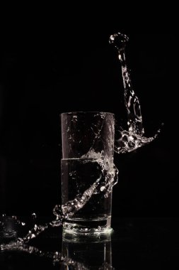 Temiz su bardağı ve koyu bir arka planda sıçrama.