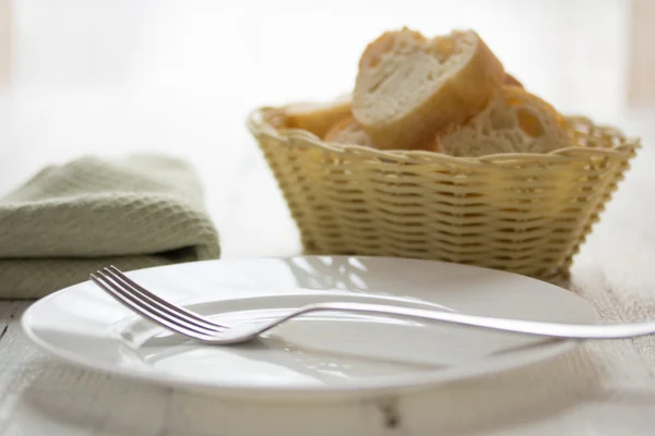 Leere Teller, Gabel und einen Korb mit Brot — Stockfoto