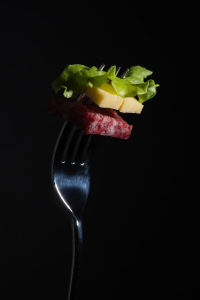 Salami, kaas en sla op een vork — Stockfoto