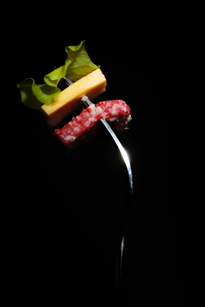 Salami, kaas en sla op een vork — Stockfoto
