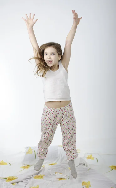 Kleines Mädchen springt isoliert auf Bett — Stockfoto