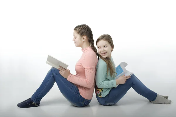 Kleine meisjes lezen boeken rug aan rug op wit — Stockfoto