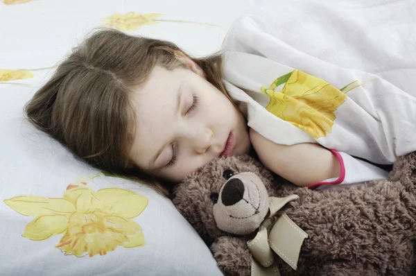 Menina dormindo na cama com ursinho de pelúcia — Fotografia de Stock