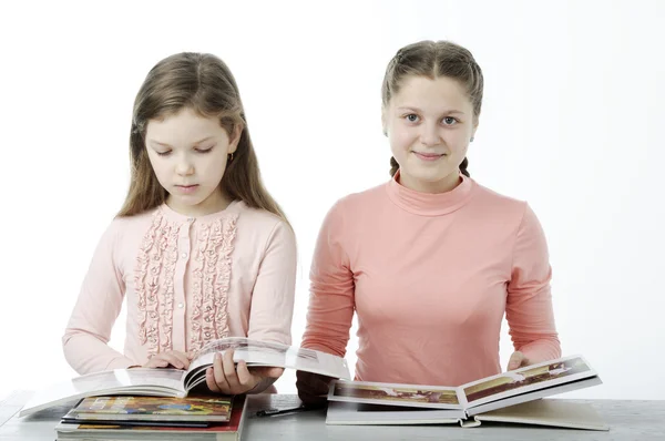 Niñas leen libros en la mesa sobre blanco Fotos De Stock