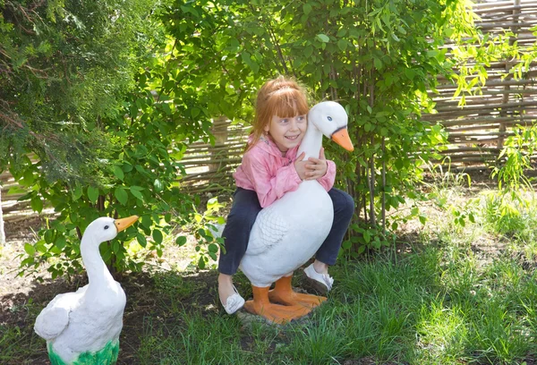 Fröhliches rothaariges Mädchen auf einer künstlichen Ente sitzend — Stockfoto