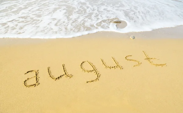 Серпень - написано піском на пляжній текстурі — стокове фото