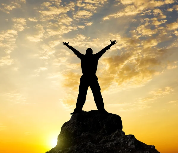 Silhouette of the person standing on a rock in beams of a declin Stock Picture