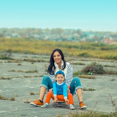 Mother and son sitting on a skateboard