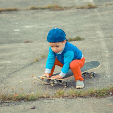 Çocuk açık havada kaykay ile eğleniyor