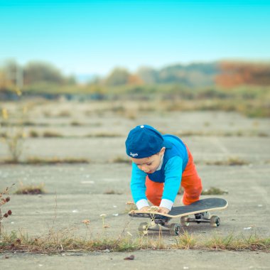Çocuk açık havada kaykay ile eğleniyor