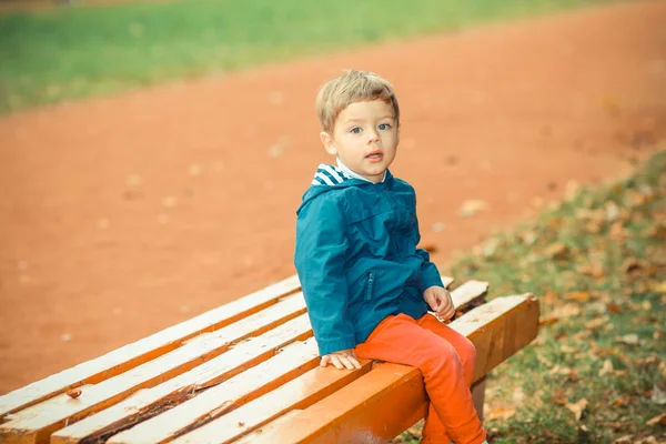 Petit garçon assis sur le banc dans le parc — Photo