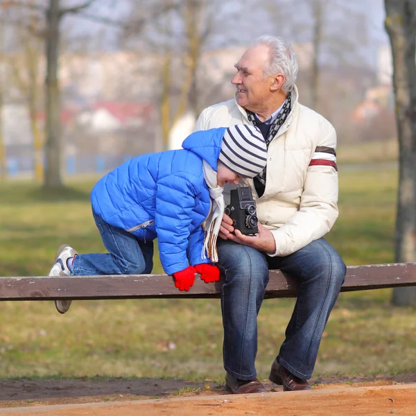 Grandfather shows grandson retro camera — Stock Photo, Image