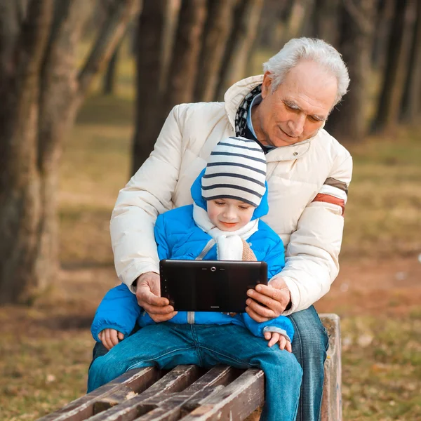 Grandfather and grandson with tablet outdoors — Stock Photo, Image