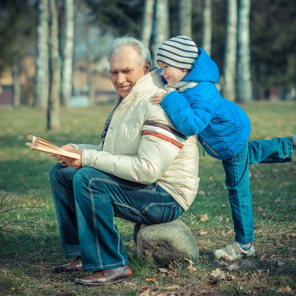 Grand-père et petit-fils avec livre en plein air — Photo