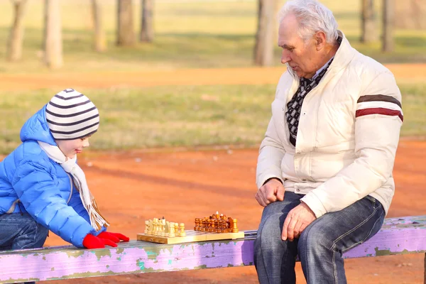 Grand-père et petit-fils jouant aux échecs à l'extérieur — Photo