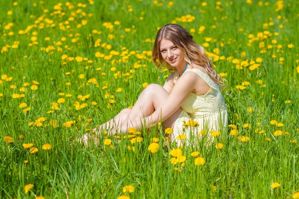 Menina bonita no campo de dentes-de-leão — Fotografia de Stock