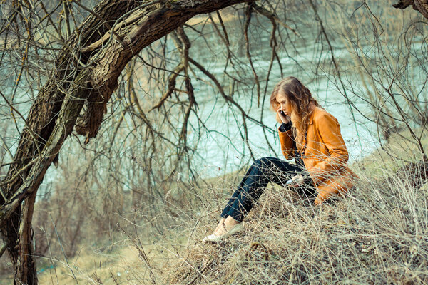 Beautiful girl hipster talking on mobile phone among the trees