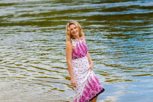 Vrouw in een lange jurk aan de kust — Stockfoto