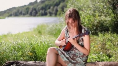 Genç ve güzel bir kız nehrin arka planında bir müzik aleti çalıyor..