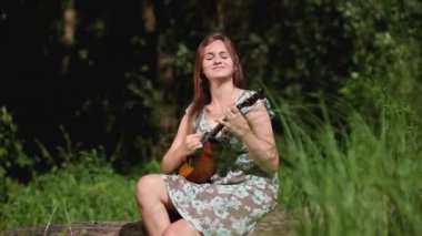 Genç ve güzel bir kız nehrin arka planında bir müzik aleti çalıyor.