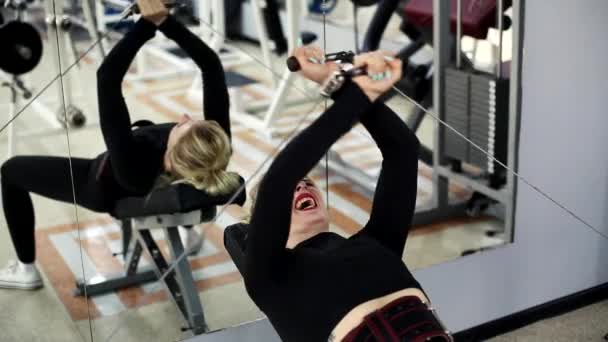 Atletische vrouw is bezig in de sportschool. Ze traint haar borstspieren in een crossover — Stockvideo