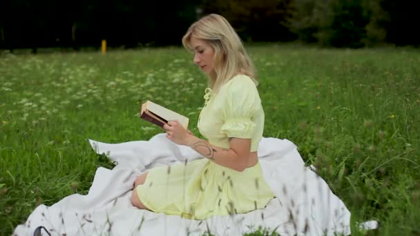美しい女の子は明るい夏の日に本を読みます — ストック動画