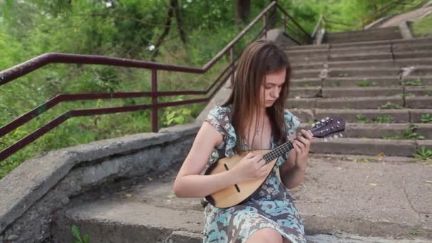 Hermosa chica lee un libro en un brillante día de verano — Vídeo de stock