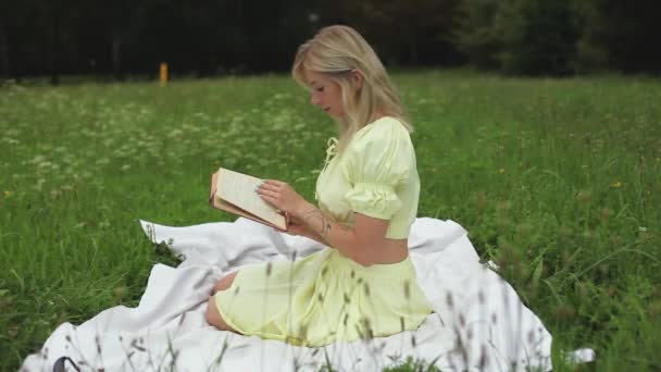 Красива дівчина читає книгу в яскравий літній день — стокове відео