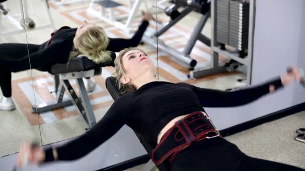 Atletische vrouw is bezig in de sportschool. Ze traint haar borstspieren in een crossover — Stockvideo