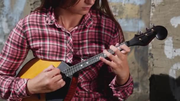 Een mooi emotioneel meisje met lang haar speelt een muziekinstrument — Stockvideo