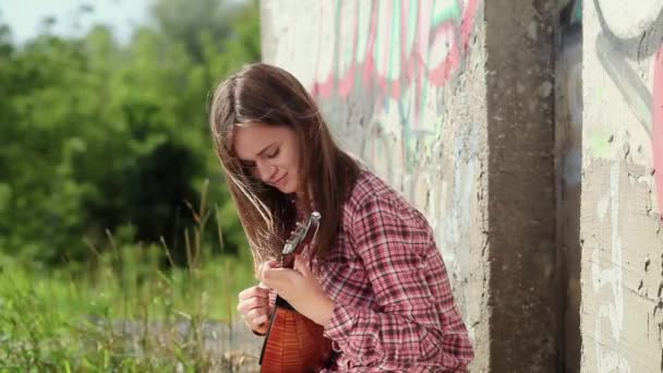 Una hermosa chica emocional con el pelo largo toca un instrumento musical. Movimiento lento — Vídeo de stock