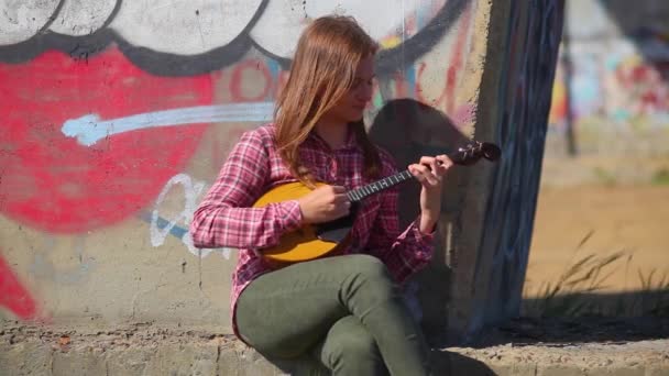 लांब केस असलेली एक सुंदर भावनिक मुलगी संगीत साधन वाजवते — स्टॉक व्हिडिओ