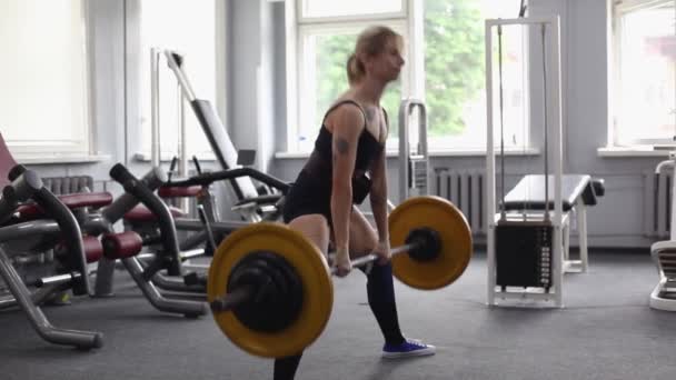 Una hermosa chica atlética se dedica al gimnasio. Barbell, punto muerto — Vídeo de stock