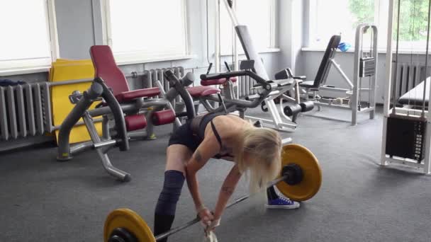 Una hermosa chica atlética se dedica al gimnasio. Barbell, punto muerto — Vídeo de stock