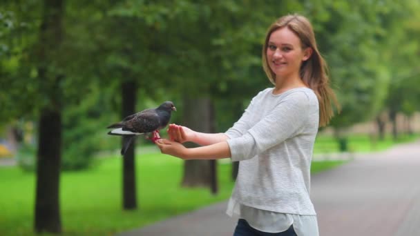Hermosa chica feliz mano alimentación palomas en el parque. — Vídeo de stock