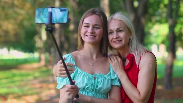 Happy mother and adult daughter take selfie in the park outdoors. — Stock Video