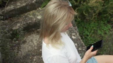 Güzel sarışın cep telefonuna bakıyor.