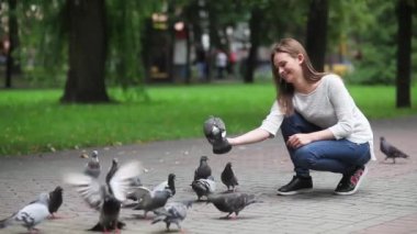 Çekici, mutlu kız parkta güvercinleri elle besliyor.. 