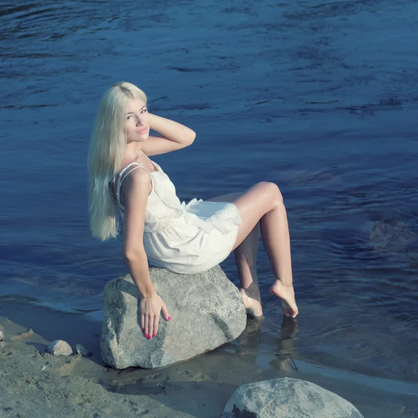 Sweet girl sitting on rock by sea — Stock Photo, Image