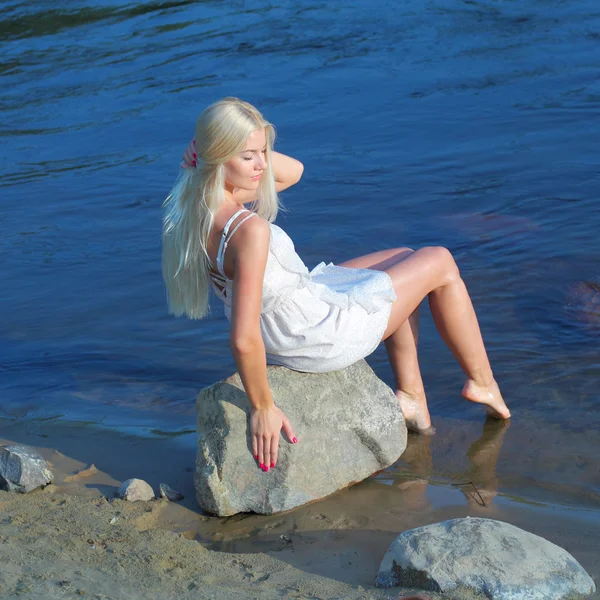 Sweet girl sitting on rock by sea — Stock Photo, Image