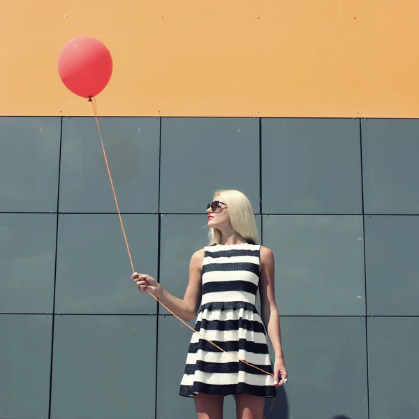 Flickan står nära vägg spegel med ballong — Stockfoto