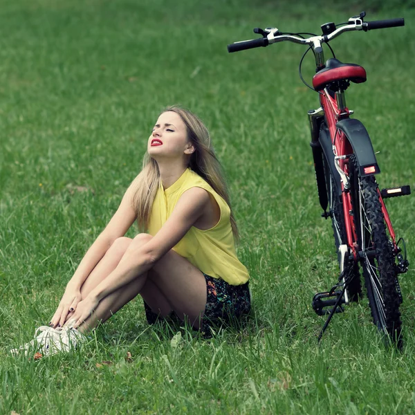 Jong meisje en fiets op groene gazon — Stockfoto