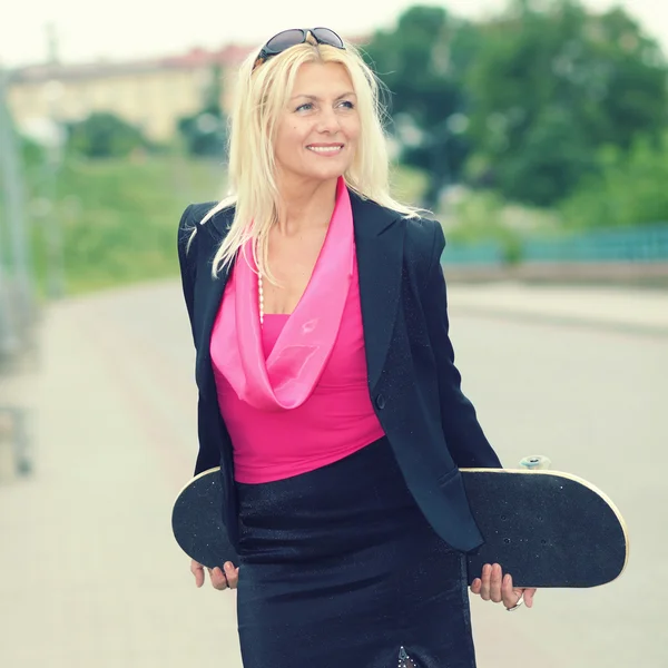 Старшая деловая женщина со скейтбордом — стоковое фото