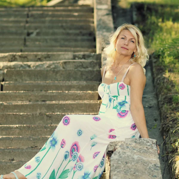 Beautiful mature blonde on stone staircase — Stock Photo, Image