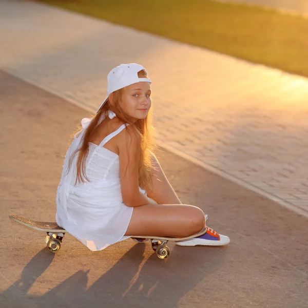 Meisje in witte jurk op skateboard — Stockfoto