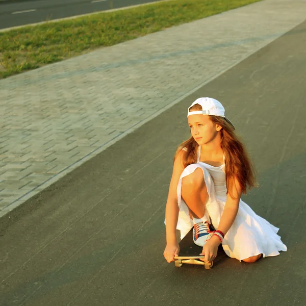 Flicka i vit klänning på skateboard — Stockfoto